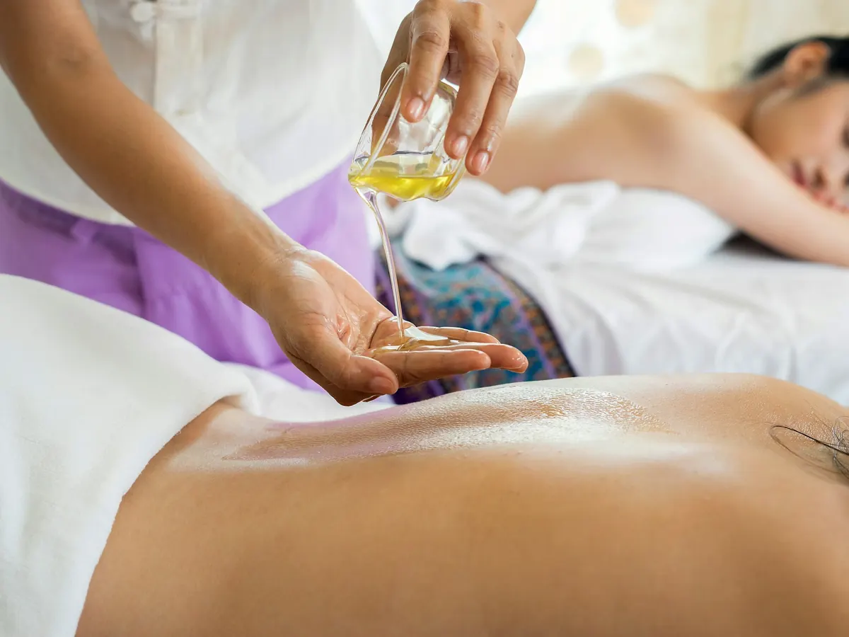 Application d’huile de massage sur le dos avant un travail en profondeur